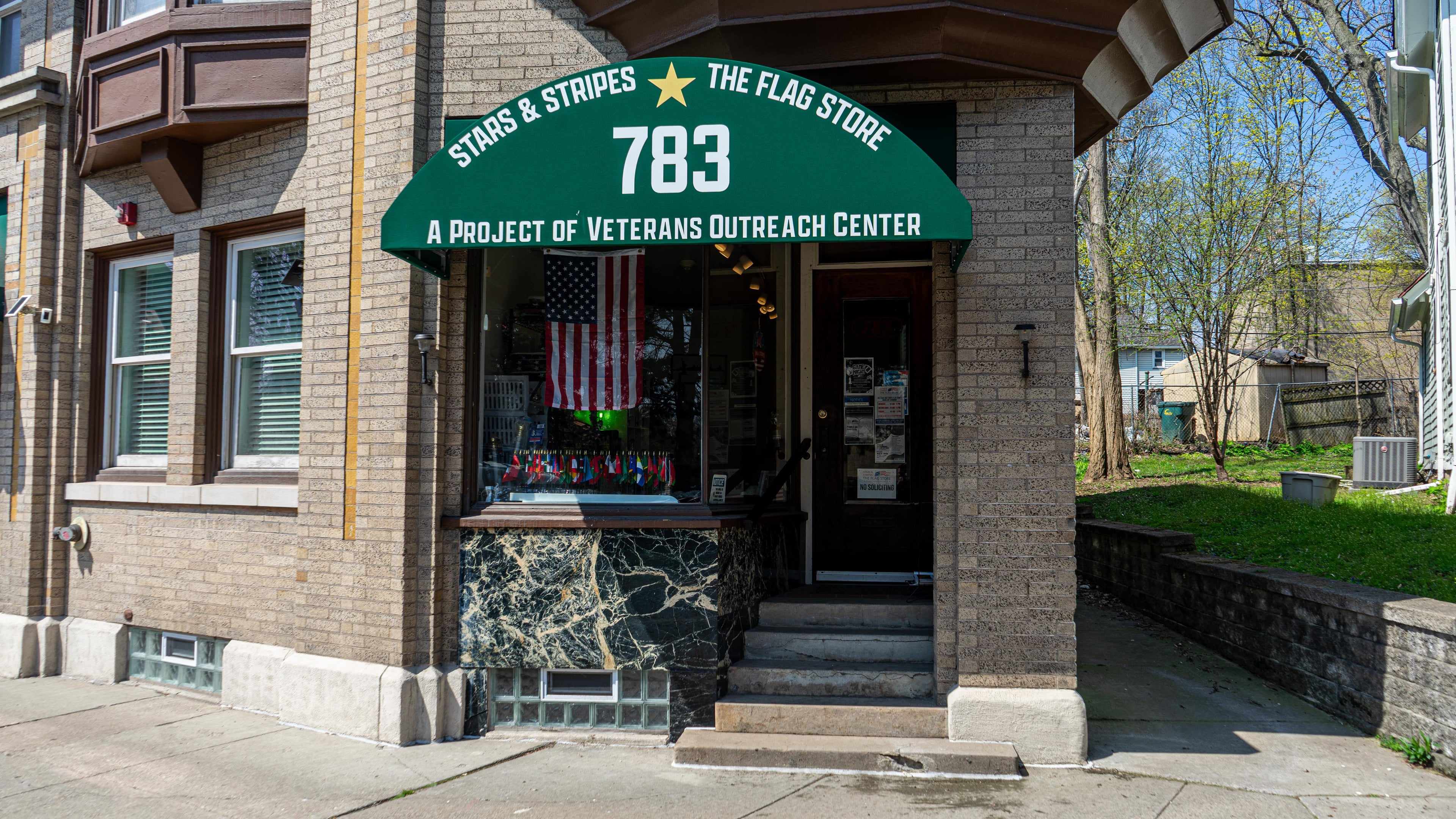 Building entrance with a green awning displaying 'Stags & Stripes The Flag Store 783' and 'A project of Veterans Outreach Center'.